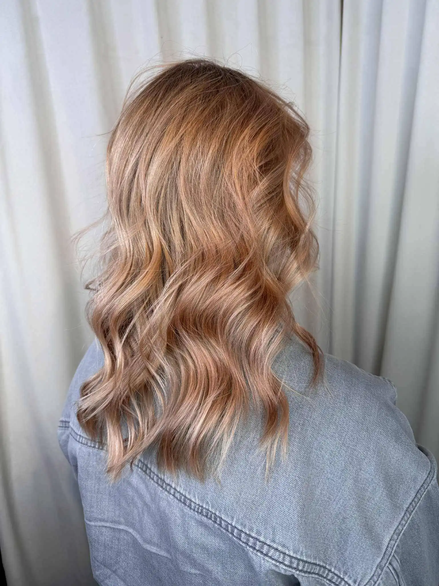 Hår i peachy pink-ton med slingor och balayage som ger mjuk dimension.